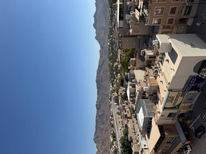 Paisaje urbano con edificios y montañas al fondo.