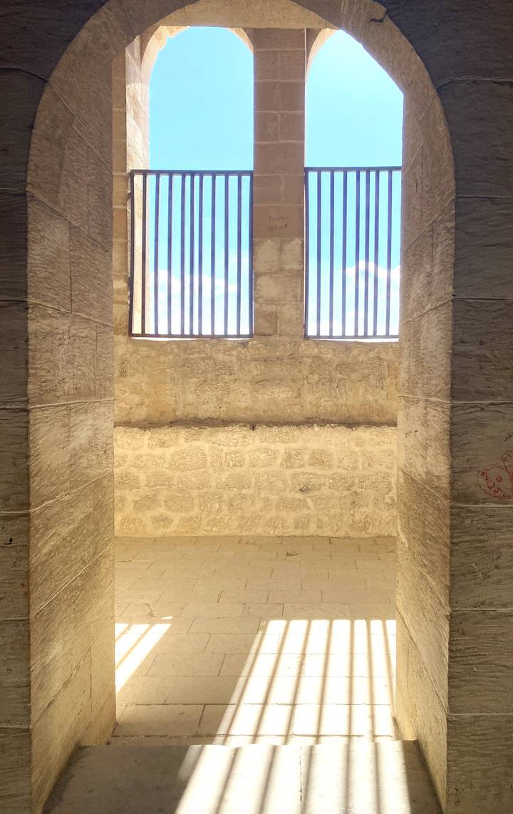 Pared interior de piedra con ventanas enrejadas.