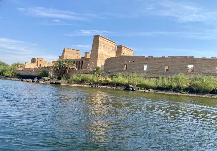 Ruinas de un templo antiguo a lo largo de la orilla de un río bajo un cielo despejado.