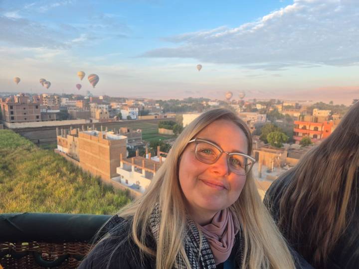 Personne en montgolfière avec ville et ballons en vue.