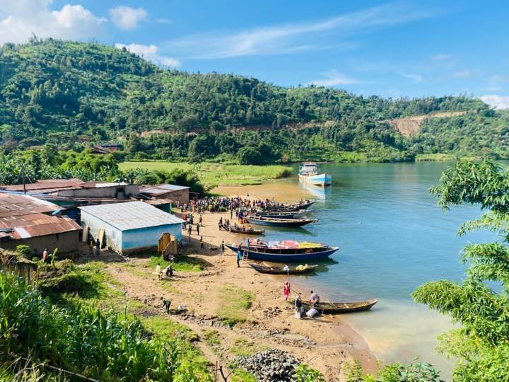 Petits bateaux et personnes au bord d'un lac au Rwanda.