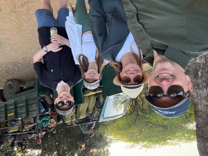 Familia lista para una aventura de safari, de pie junto a un vehículo abierto.