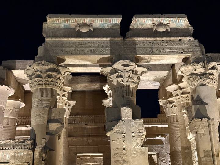 Piliers égyptiens antiques illuminés la nuit.