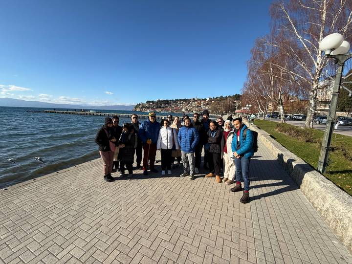 Grupo de turistas parados junto a un sendero a la orilla del lago.