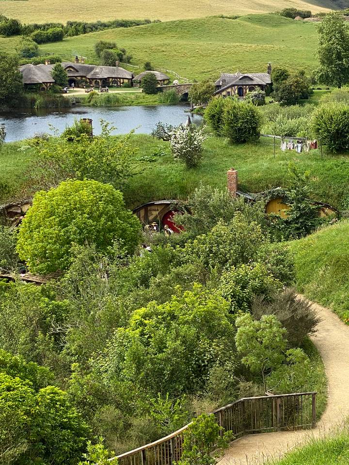 Maison de type hobbit construite dans une colline entourée d'une végétation luxuriante.