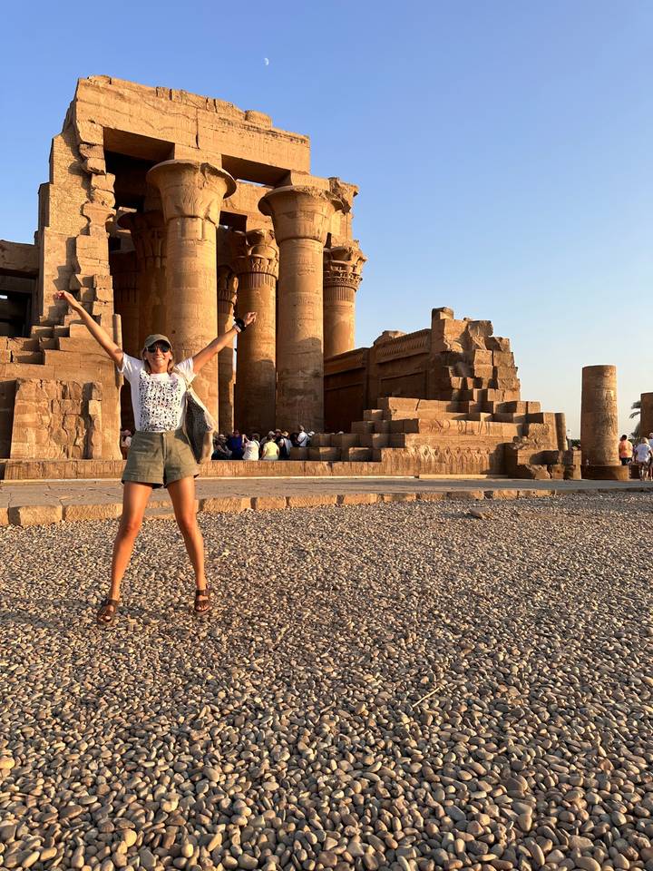 Une femme posant avec enthousiasme devant des colonnes antiques.