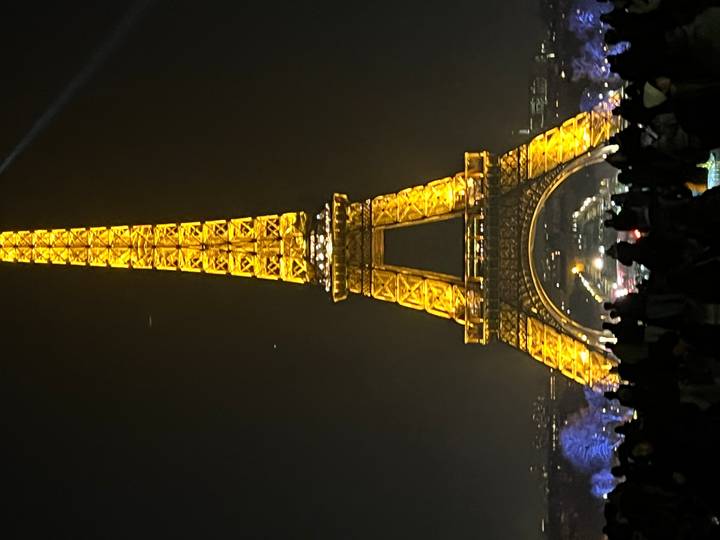 La Tour Eiffel illuminée la nuit avec des gens au premier plan.