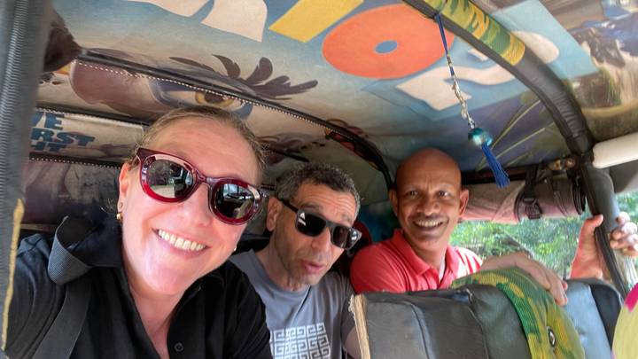 Trois personnes souriantes à l'intérieur d'un tuk-tuk, vues de l'intérieur.