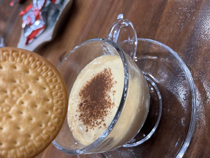 Close-up of a coffee cup with a biscuit and cream.