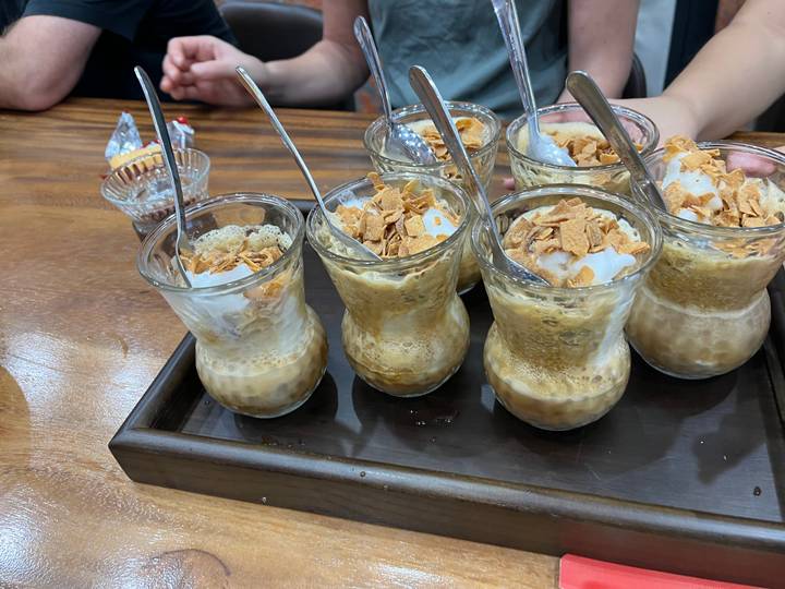 Multiple glass cups filled with a creamy coffee and topped with flakes.
