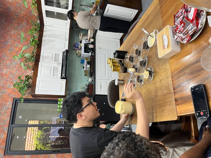 Person preparing multiple coffee beverages on a table.