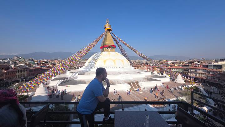 Une personne est assise sur un balcon avec vue sur le stupa de Boudhanath.