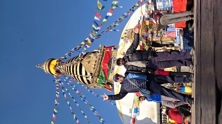 Deux personnes posant devant un stupa avec des drapeaux de prière.