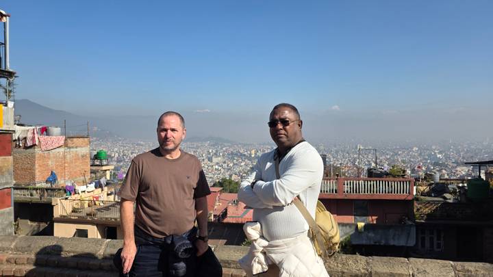 Deux personnes se tiennent debout avec une vue sur un paysage urbain en arrière-plan.