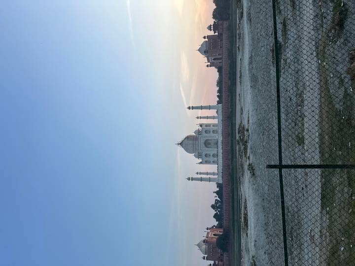 Blick auf das Taj Mahal von einem kahlen Feld aus bei Abenddämmerung.