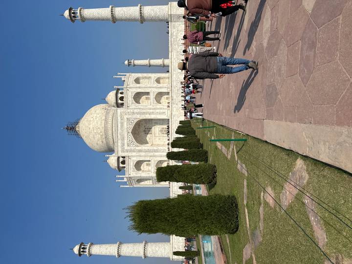 Touristen, die im Sonnenlicht auf das Taj Mahal zugehen.