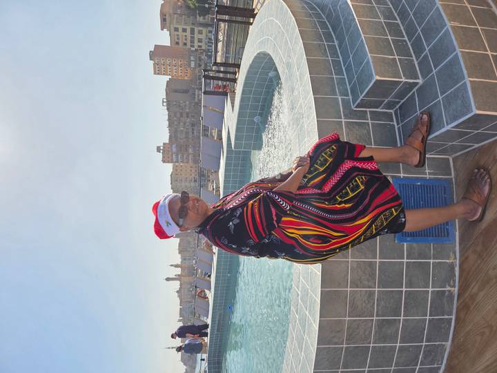 Person sitting by a pool with a Santa hat.