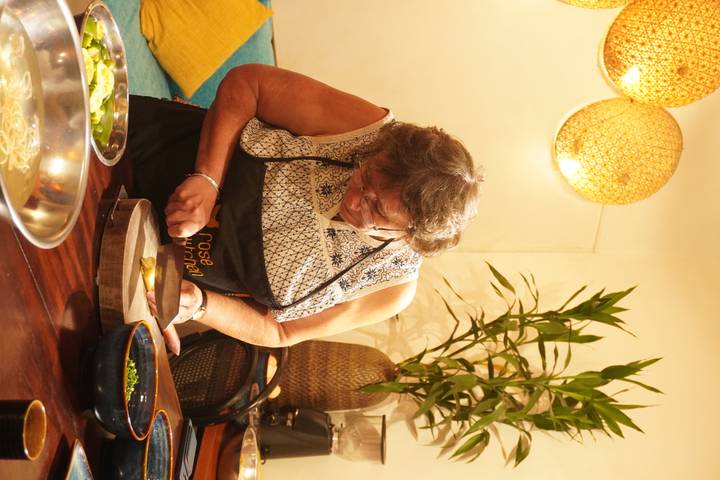 Mujer mayor cortando ingredientes en una clase de cocina.