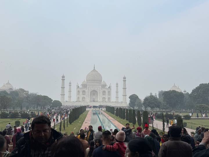Zona turística con el Taj Mahal a la distancia y muchos visitantes.