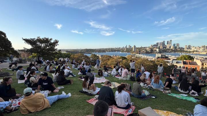 Personas disfrutando un picnic con vista al horizonte urbano y la bahía.