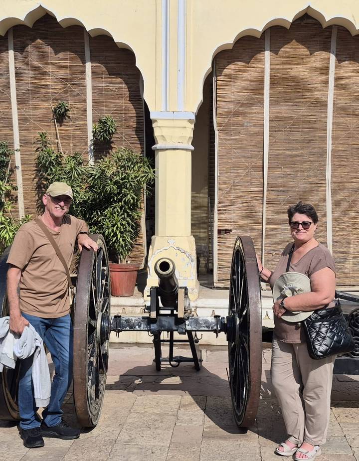 Pareja posando con un cañón antiguo en un sitio histórico.