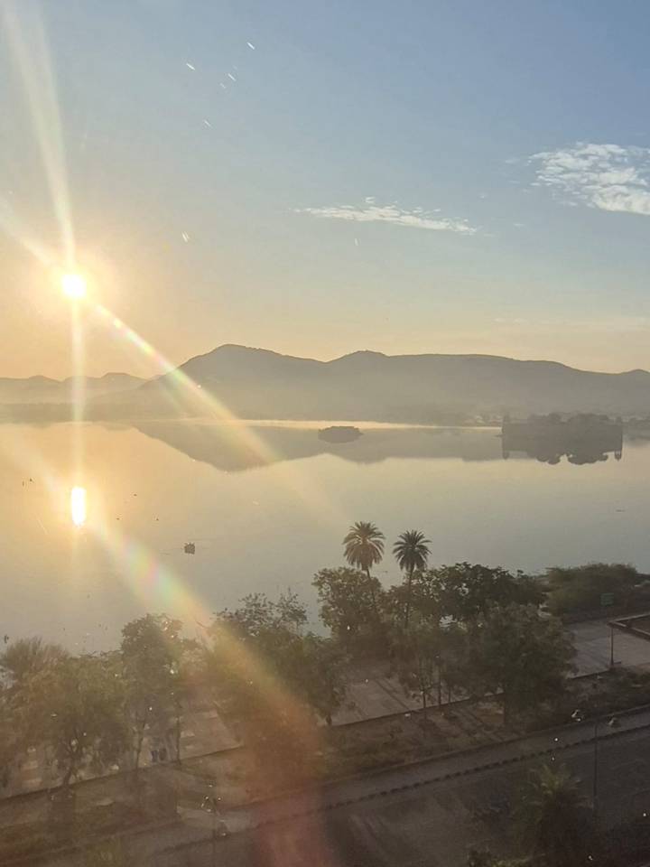 Amanecer pintoresco sobre un lago tranquilo con montañas silueteadas.