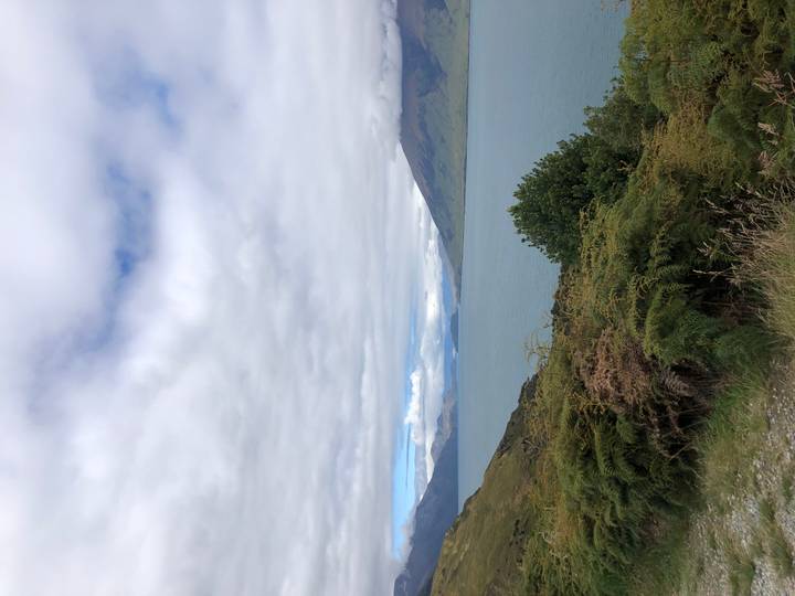 Con vista a un gran lago con colinas y un cielo nublado.