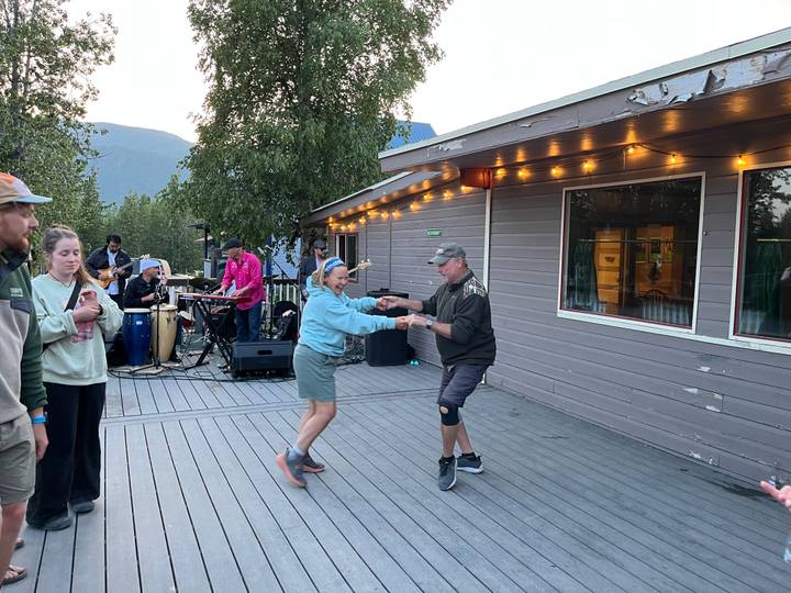 Personas bailando en un porche con una banda en vivo de fondo.