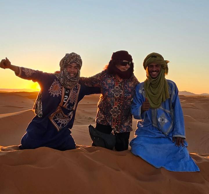 Grupo de personas vistiendo atuendo tradicional en el desierto.