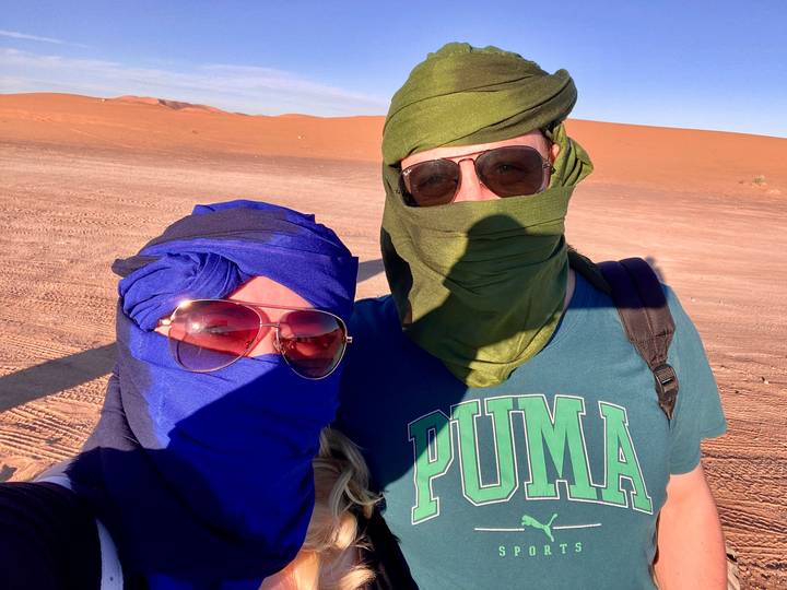 Dos personas con pañuelos en la cabeza posando en el desierto.