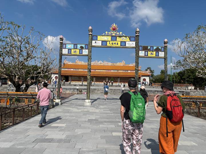 Tourists walking into a grand entrance of a historic site.