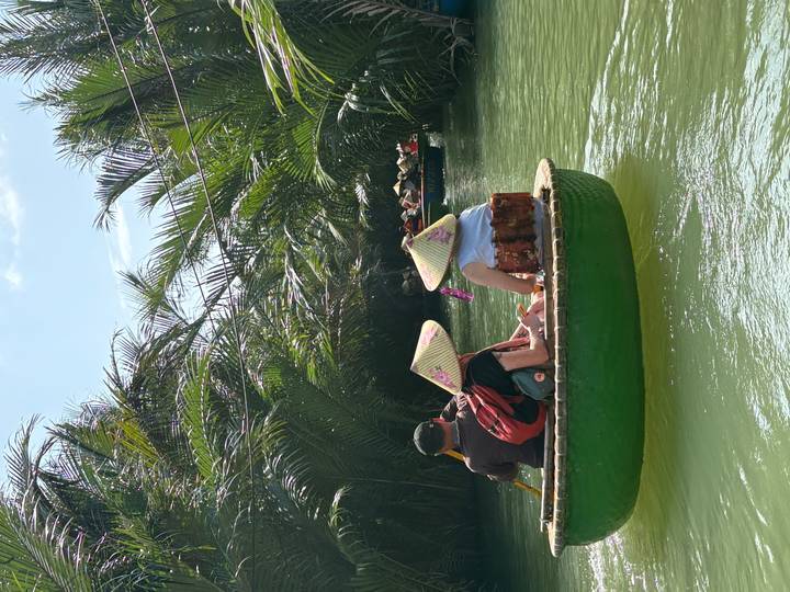 People in a round bamboo boat on a lush river.