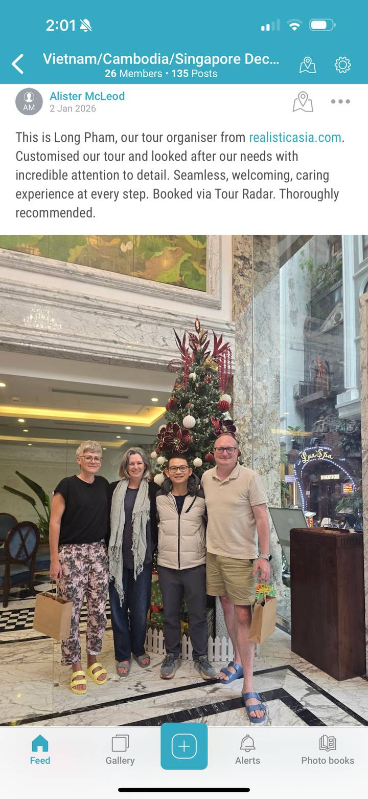 Group of people posing in front of a decorated Christmas tree indoors.