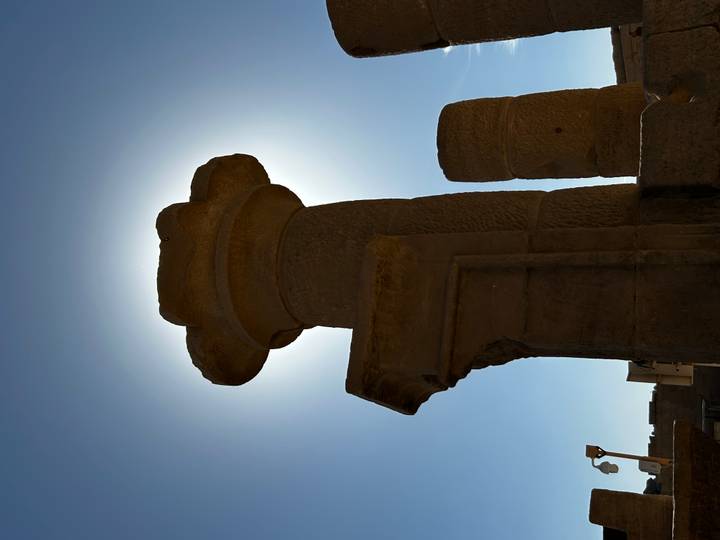 Une colonne antique en silhouette contre le soleil.