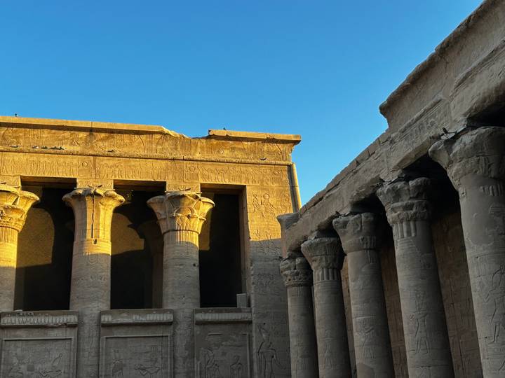 Anciennes colonnes de temple avec des hiéroglyphes sous un ciel bleu.