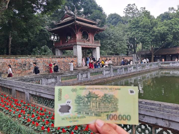 Grupo de personas cerca de un templo tradicional con un estanque en primer plano.