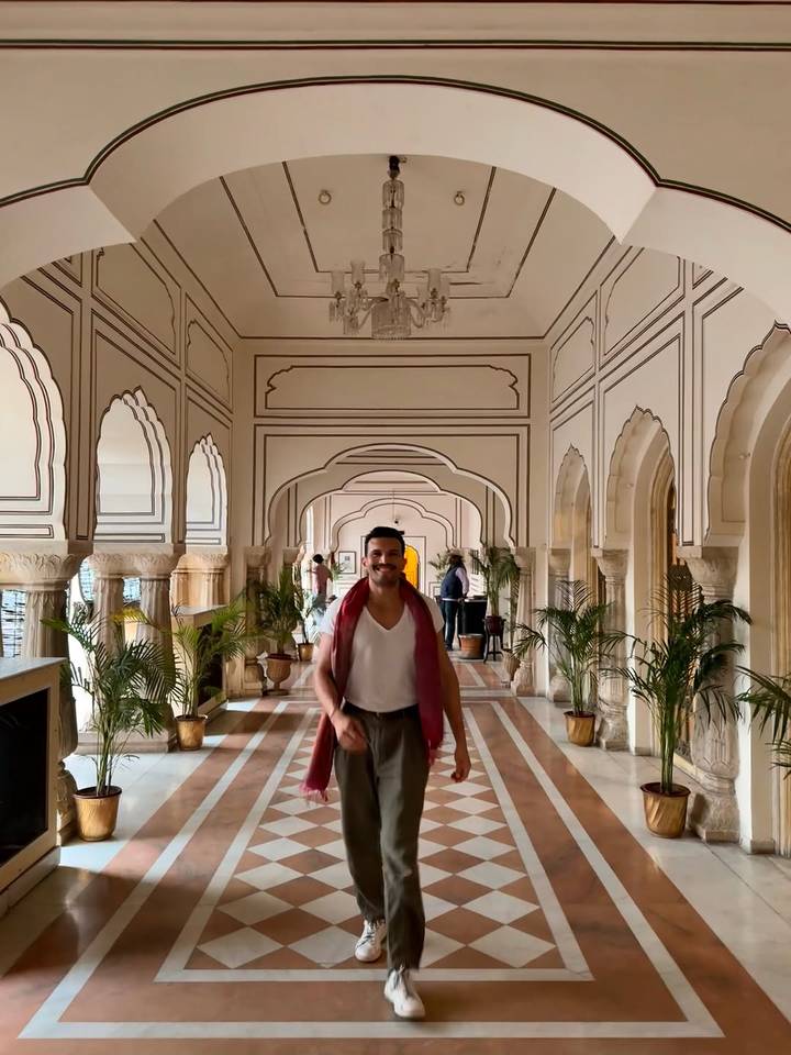 Hombre caminando por un corredor histórico con pasillos arqueados.