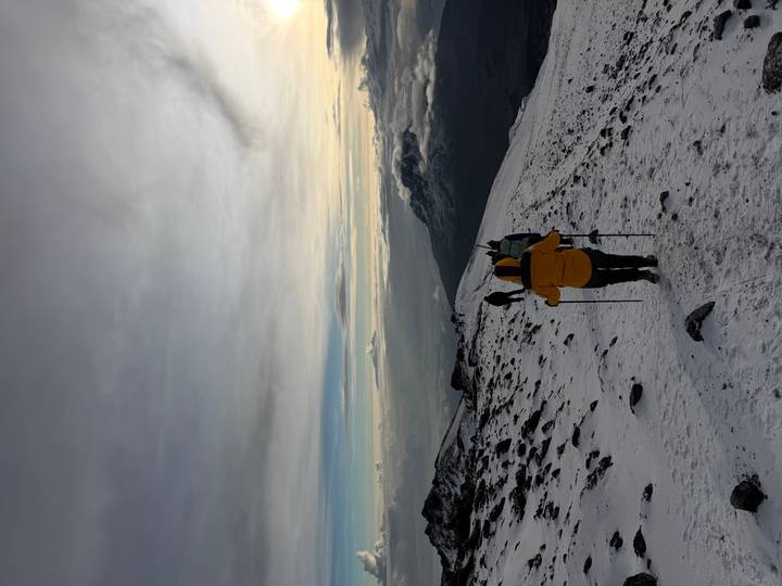 Excursionista con equipo de invierno caminando por un sendero nevado de montaña.