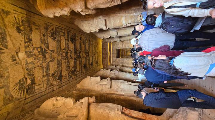 Interior of an ancient Egyptian temple with large statues and many tourists.