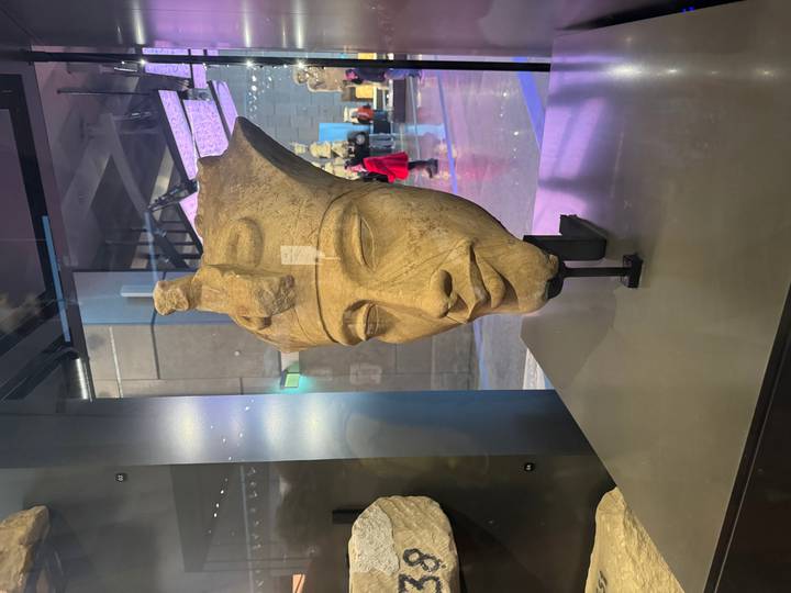 Decorative ancient bust on display in a museum with visitors.