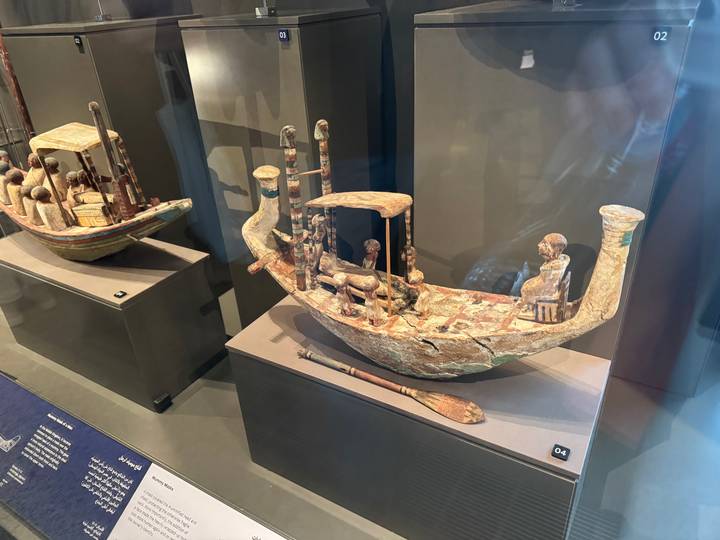 Ancient model of a boat with people inside on display.