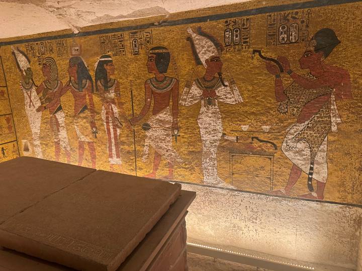 Colorful hieroglyphs on a tomb wall with a stone sarcophagus.