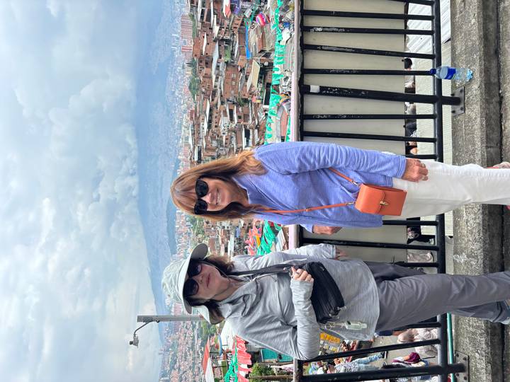 Deux femmes souriantes avec un paysage urbain en arrière-plan.