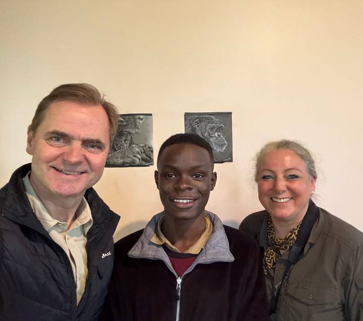 Dos personas sonriendo en interiores con un dibujo de chimpancés en el fondo.