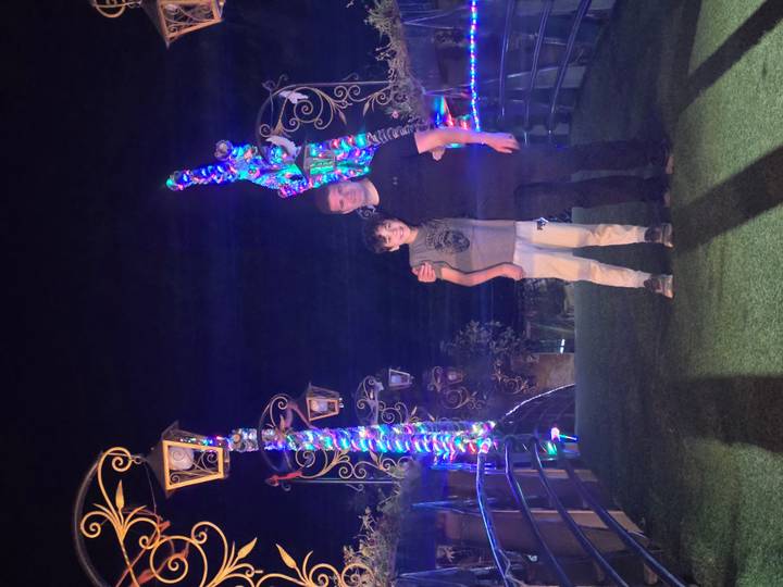 Dos personas posando bajo luces coloridas en la noche.