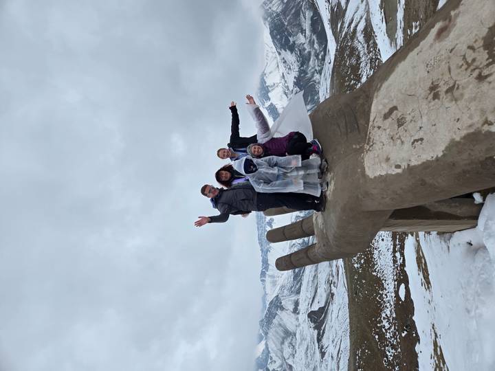 Grupo de personas posando en una estatua de mano gigante en un entorno nevado.