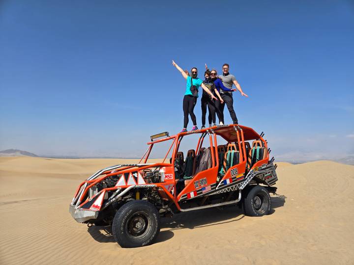 Grupo de personas posando en un buggy en el desierto.