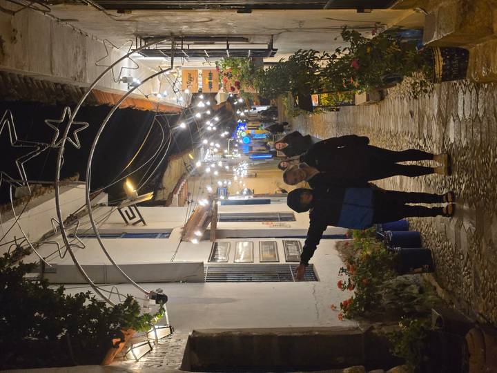 Dos personas de pie en una calle decorada por la noche.