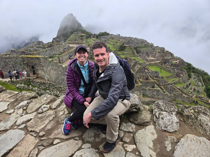 Pareja sentada con Machu Picchu de fondo.