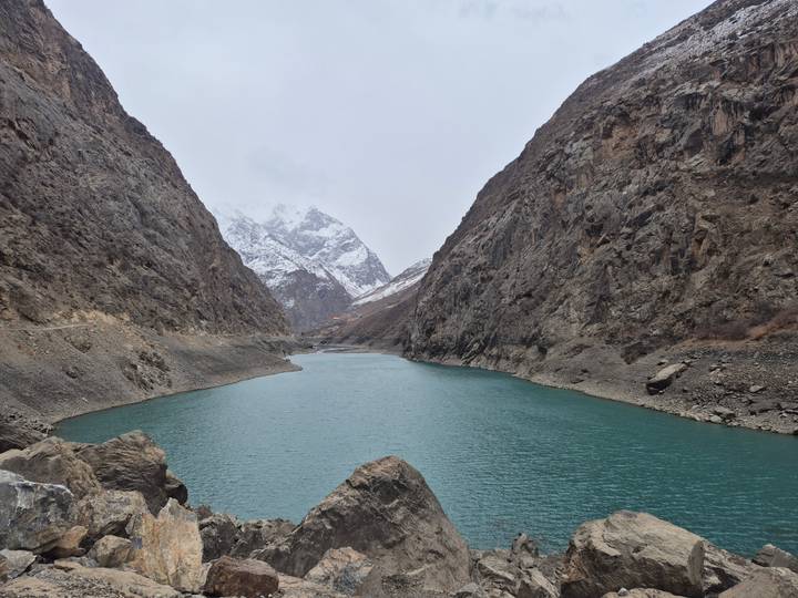 Scenic mountain lake with rocky cliffs and snowy peaks.
